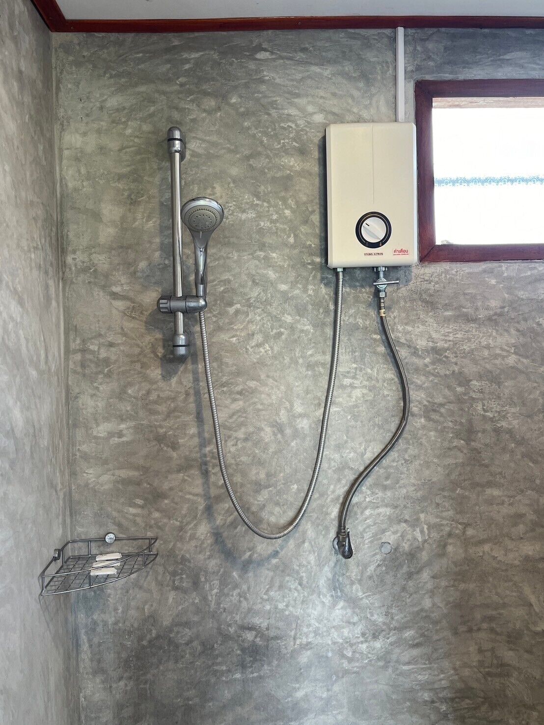 A shower with a handheld showerhead and a wall-mounted control unit.