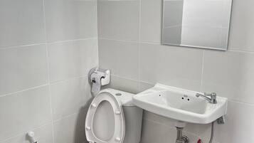 A bathroom with a toilet, sink, and a small trash bin.