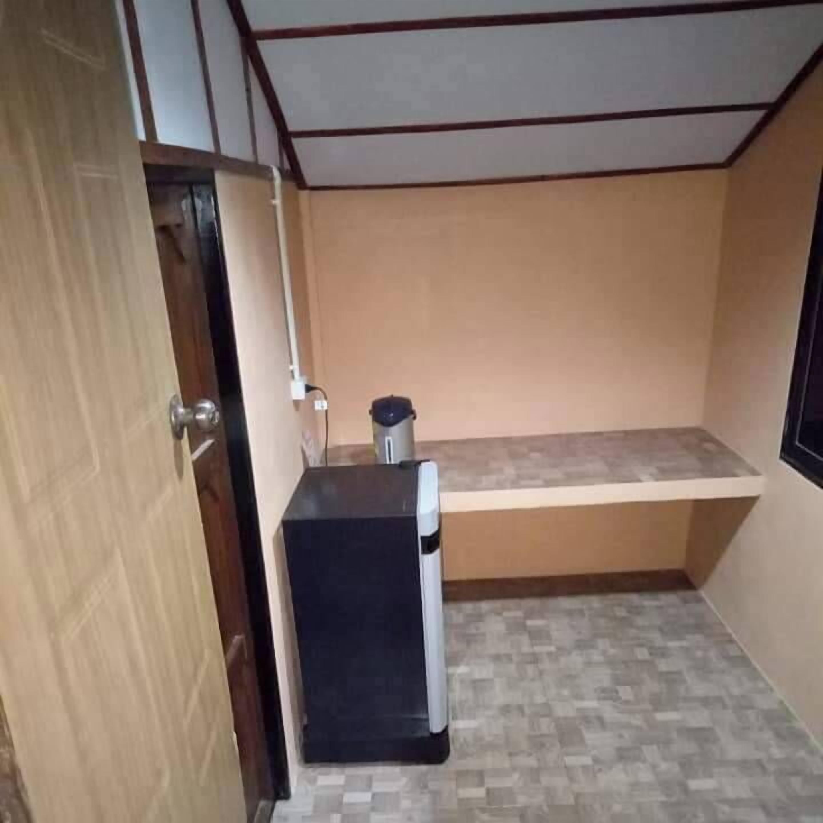 A compact kitchen with a refrigerator, a small countertop, and a tiled floor.