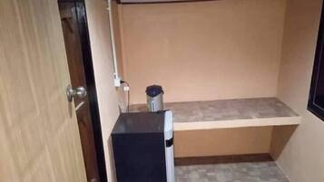 A compact kitchen with a refrigerator, a small countertop, and a tiled floor.