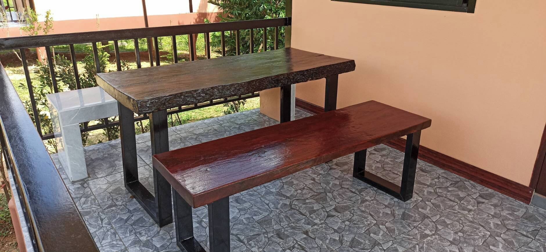 A balcony with two wooden tables and a bench.