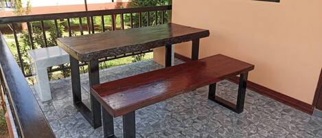 Ein Balkon mit zwei Holztischen und einer Bank.