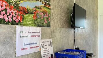 Ein Zimmer mit einer großen Blumenmalerei, einem an der Wand montierten Fernseher und einem Tablett mit Toilettenartikeln auf einem Regal.