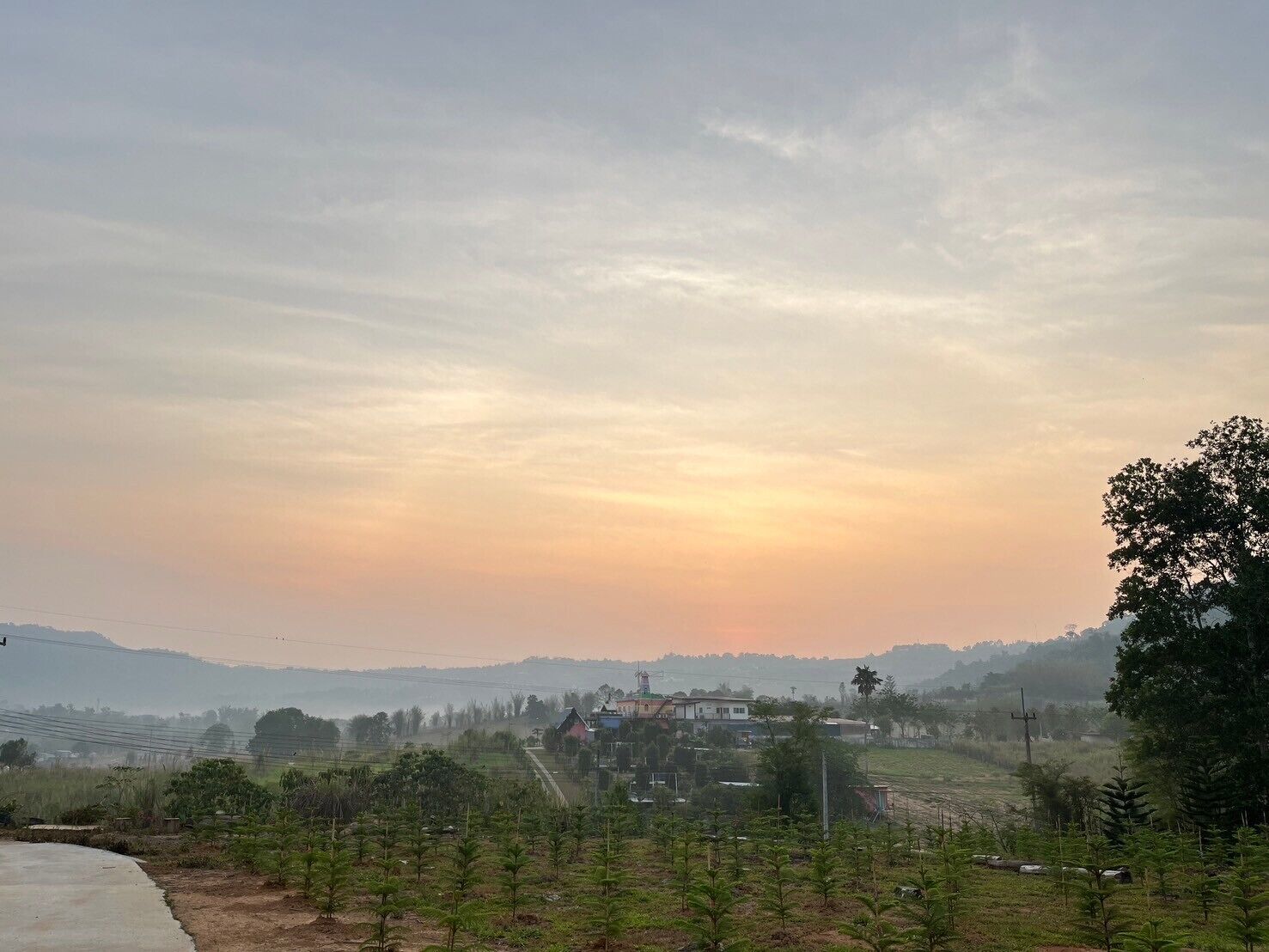 A rural landscape with a clear sky, a few houses, and a road.