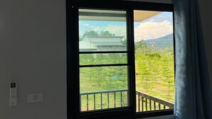 Una habitación con un ventanal grande, una cortina y un termostato en la pared.
