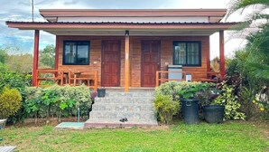 Una casa de madera con un porche, dos ventanas y una puerta.
