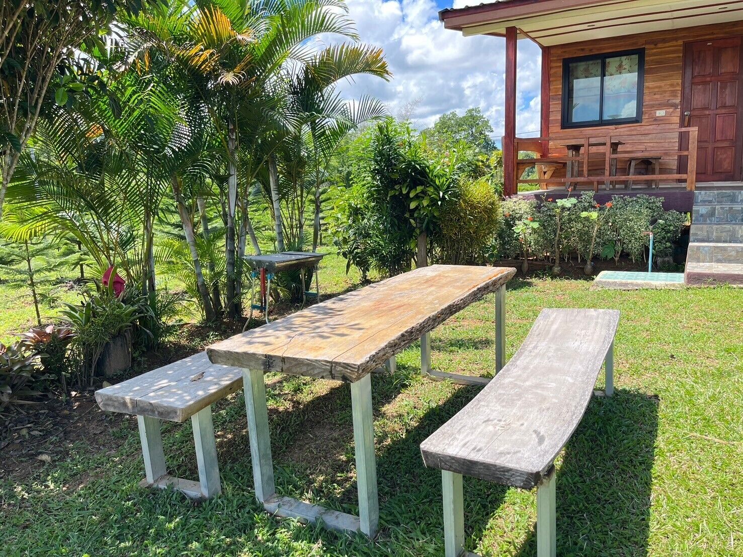 Una mesa de picnic de madera con bancos en un exuberante jardín.