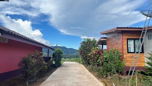 Un sendero que lleva a dos edificios de madera, con una montaña al fondo.