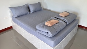 Una cama bien hecha con ropa de cama gris y dos toallas dobladas.