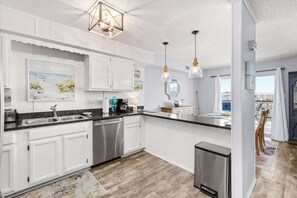 Een moderne keuken met witte kasten, roestvrijstalen apparatuur en een groot eiland.