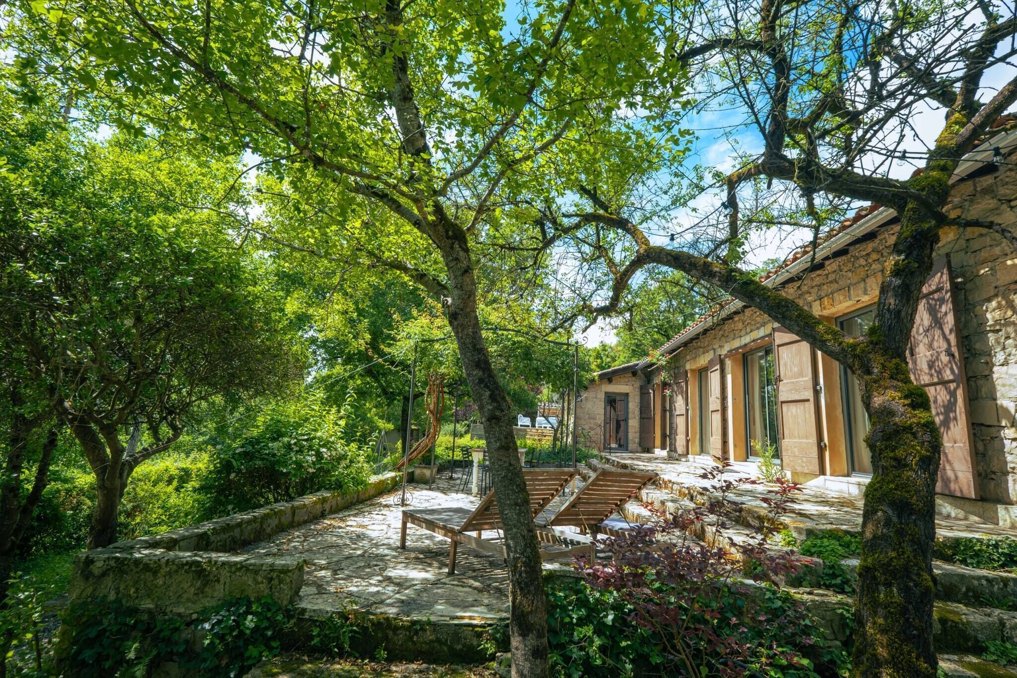 A courtyard with stone steps, wooden benches, and a stone building with large doors.