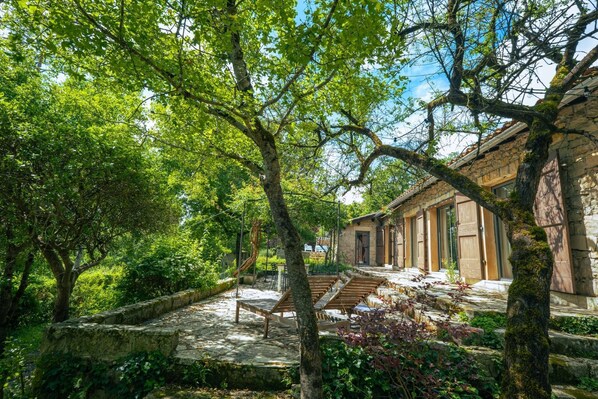 A courtyard with stone steps, wooden benches, and a stone building with large doors.