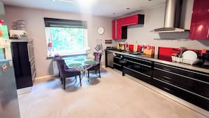 Una cocina moderna con comedor, que incluye una mesa de vidrio, sillas moradas y armarios rojos.