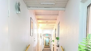 Un pasillo de hotel con escaleras alfombradas, paredes blancas y un radiador a la derecha.