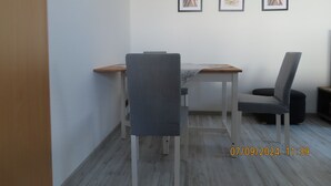 Een moderne kamer met een eettafel, twee stoelen en drie ingelijste foto’s aan de muur.