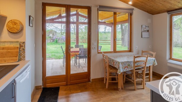 A kitchen with wooden cabinets, a built-in dishwasher, and a dining area with a table and chairs. - Comfortable 2-bedroom cottage with garden, pets allowed, Wifi, parking (Montilliers)