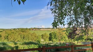 A rural landscape with a wooden fence, a pond, and a view of green fields and trees. - Comfortable 2-bedroom cottage with garden, pets allowed, Wifi, parking (Montilliers)
