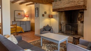 A cozy living room with a fireplace, a dining area with a yellow table, and a grey sofa. - Comfortable 2-bedroom cottage with garden, pets allowed, Wifi, parking (Montilliers)