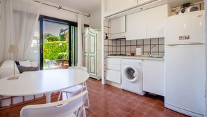 Una cocina compacta con lavadora, un comedor con mesa y sillas, y vistas a zonas verdes exteriores.