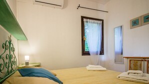 Un dormitorio con una cama, una mesita de noche, una ventana con cortinas y un aire acondicionado de pared.