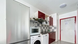 Cocina compacta equipada con refrigerador, microondas, horno y lavadora.