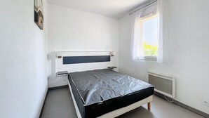 Una habitación pequeña y limpia con una cama individual, una ventana con cortinas y un radiador.