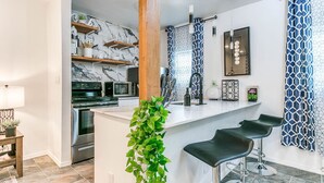 Une cuisine moderne avec un dosseret en marbre, des appareils en acier inoxydable et un coin bar avec des tabourets.