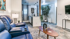 Un salon moderne avec un canapé en cuir bleu, une table basse en bois et un tapis à motifs.