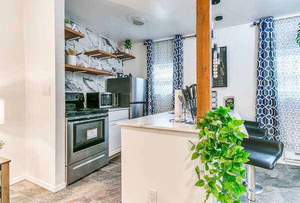 A modern kitchen with stainless steel appliances, marble backsplash, and a central island. - Amazing location, just short walk to Oklahoma City University and 23rd street restaurants (Oklahoma city)