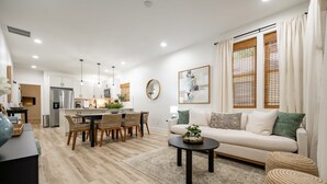 Ein modernes Wohnzimmer mit einer Couch, einem Couchtisch und einem Essbereich mit Stühlen.
