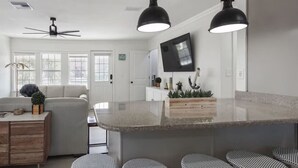 Eine moderne Küche mit einer großen Kochinsel, Pendelleuchten und einem Deckenventilator.