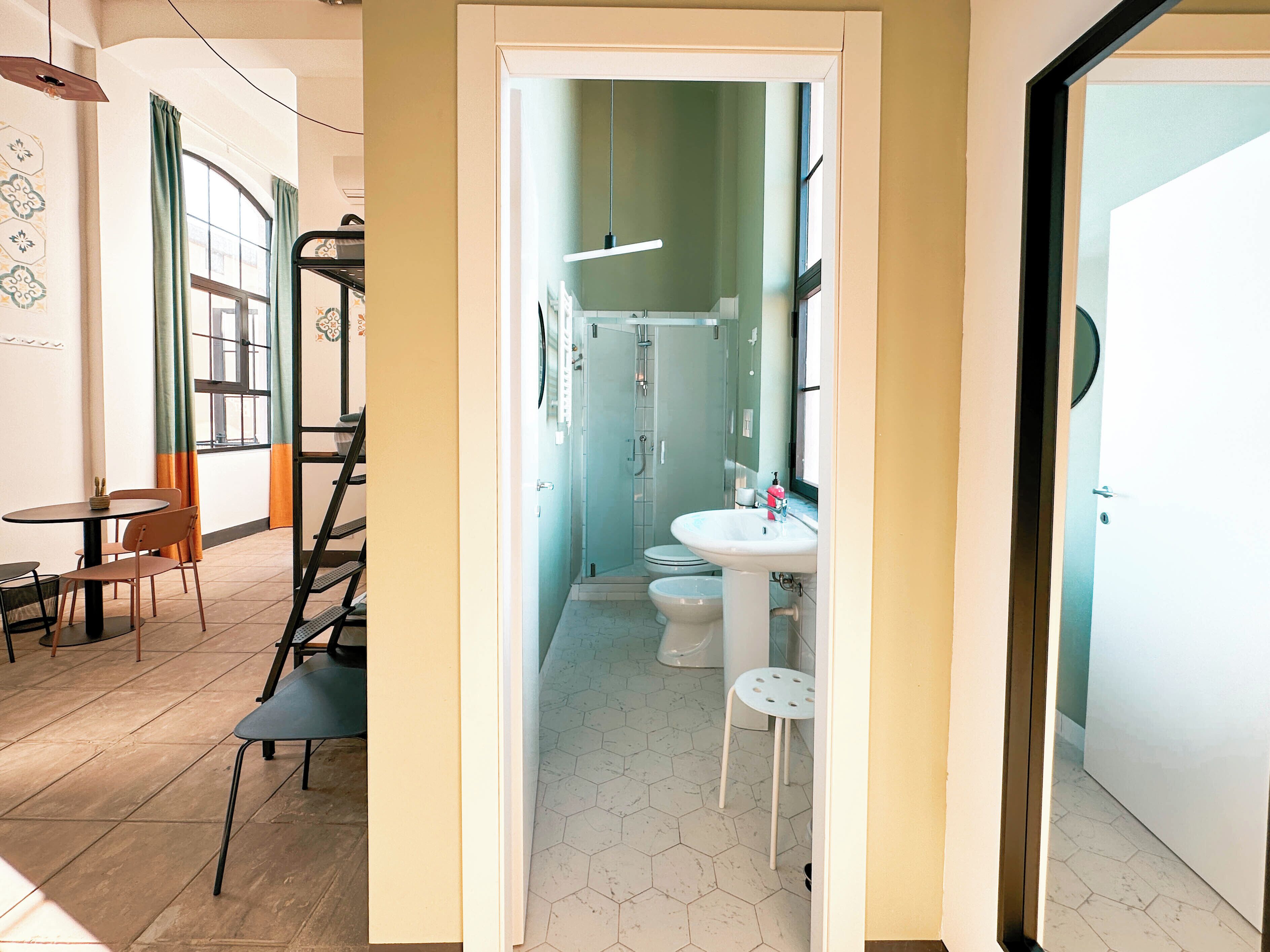 Un interior moderno con comedor, escalera y baño con ducha, inodoro y lavamanos.