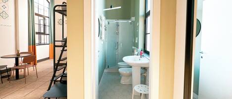 Un interior moderno con comedor, escalera y baño con ducha, inodoro y lavamanos.