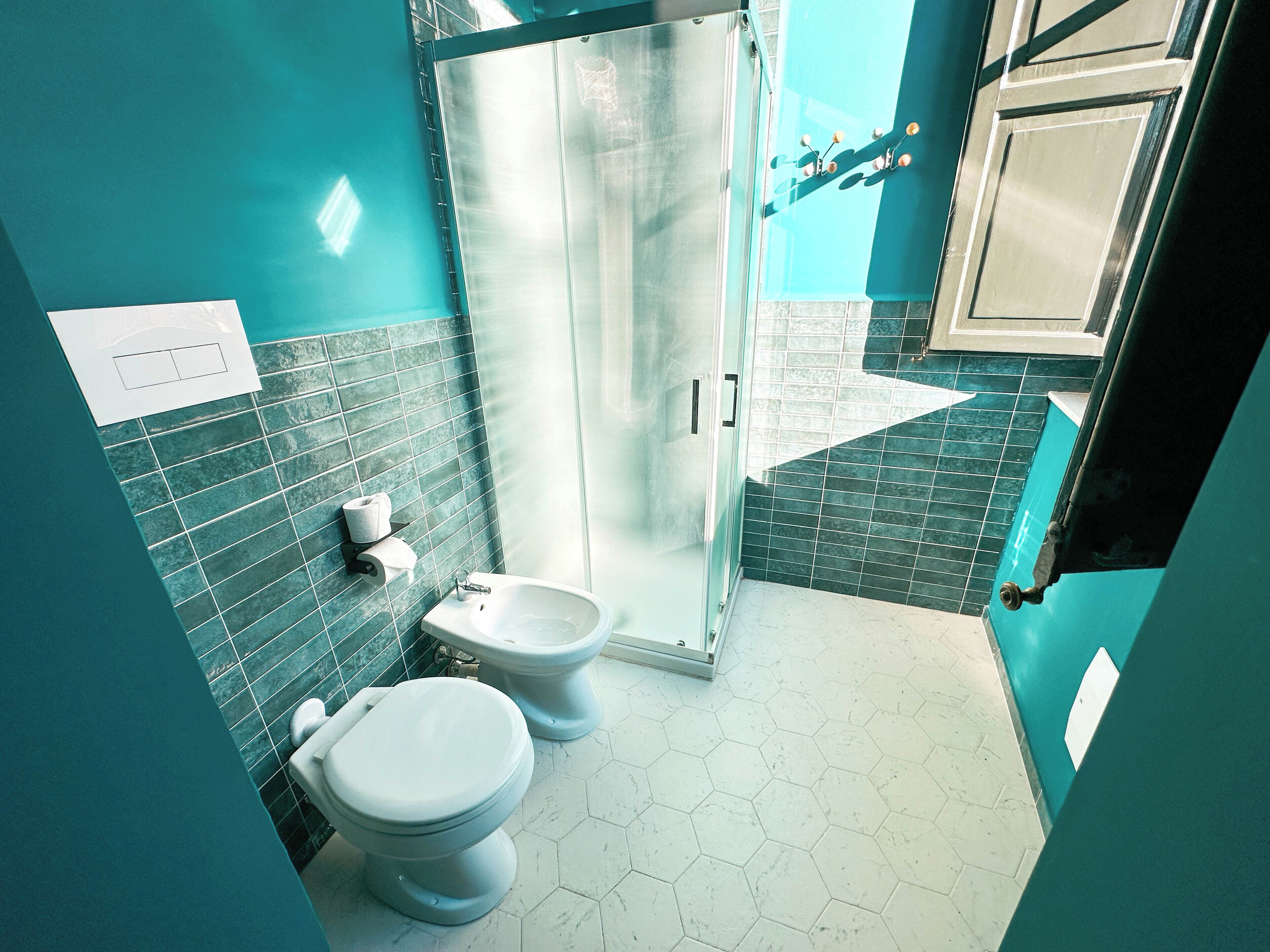 A bathroom with two toilets, a shower, and a sink.