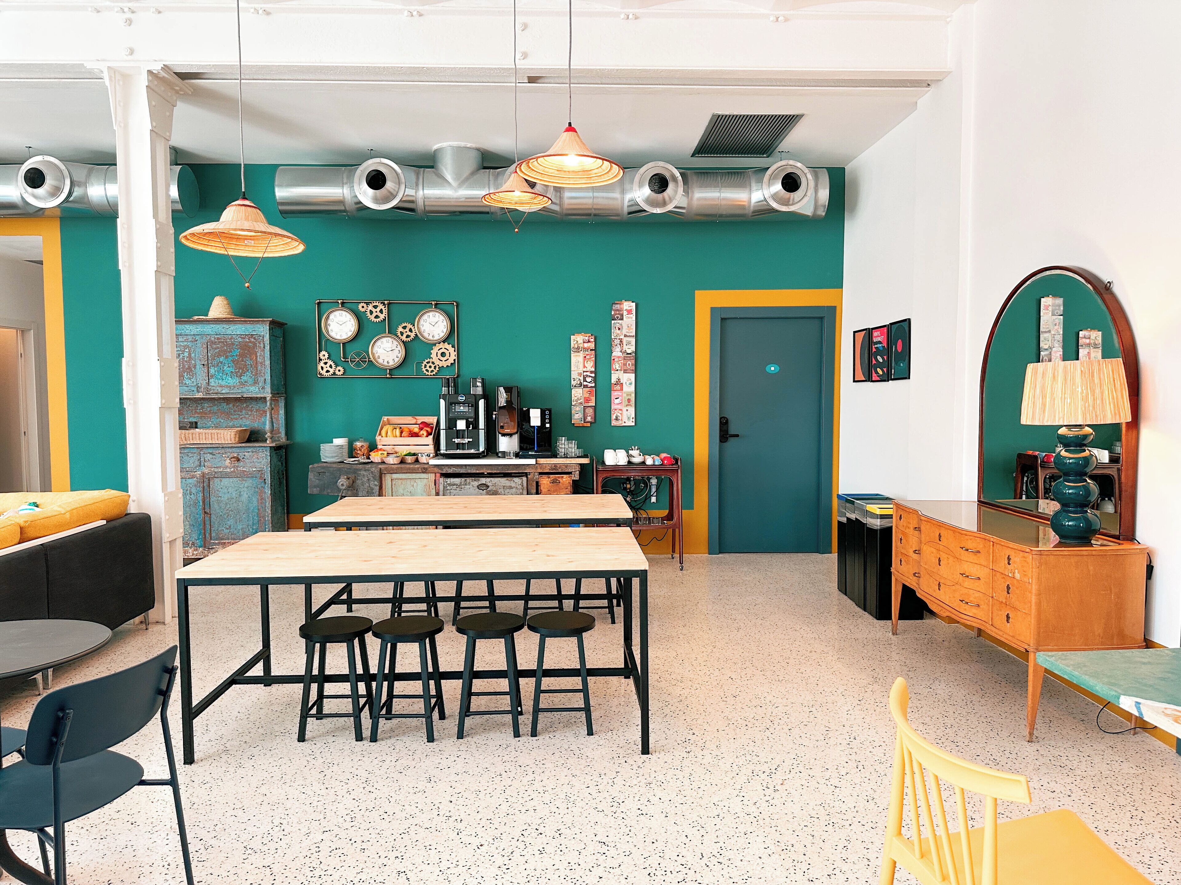 Una cocina moderna con una isla central, una cafetera y una pared de acento en color turquesa.