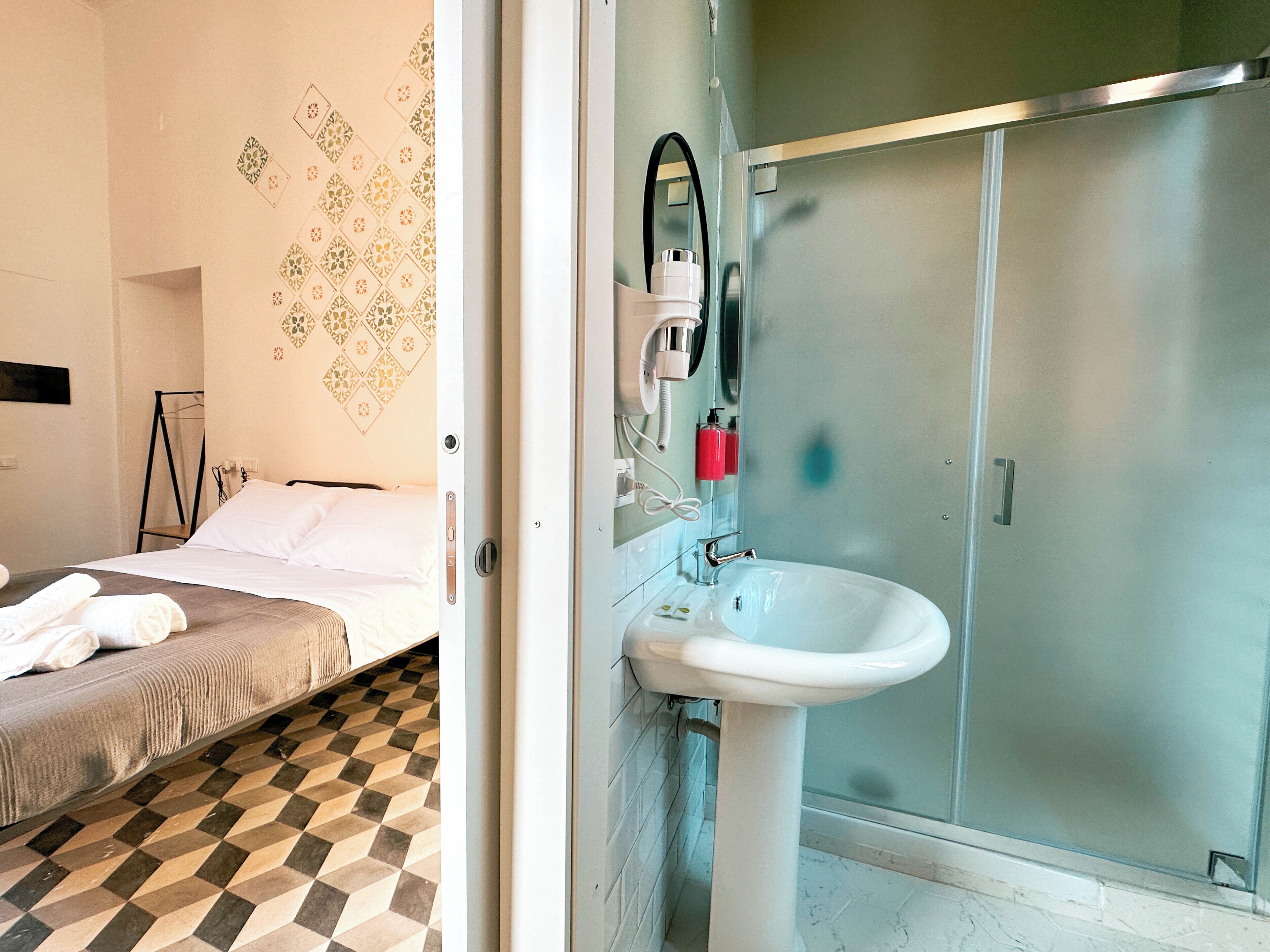 A hotel room with a bed, a bathroom with a sink, and a shower.