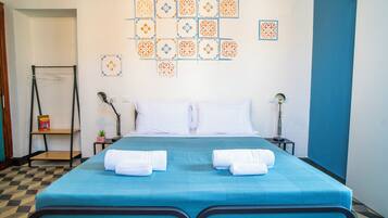 A hotel room with a bed, two bedside tables, a wall-mounted shelf, and a patterned wall decoration.