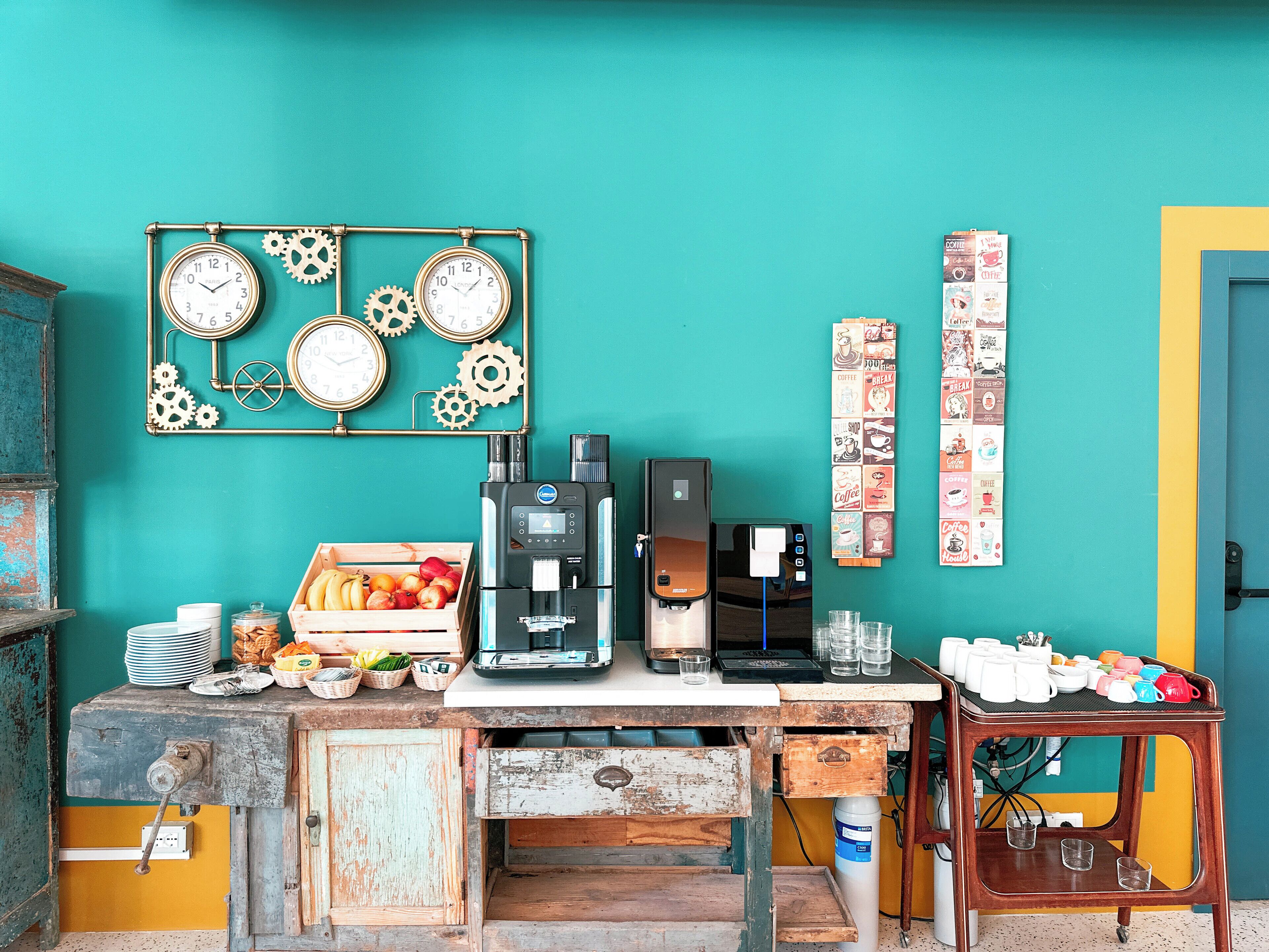 Un café au décor rustique, avec un mur de couleur turquoise, de vieilles horloges et une machine à café.