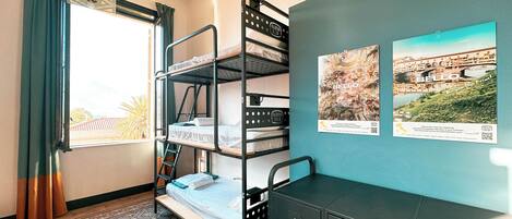 A dormitory room with bunk beds, a desk, and a cabinet.