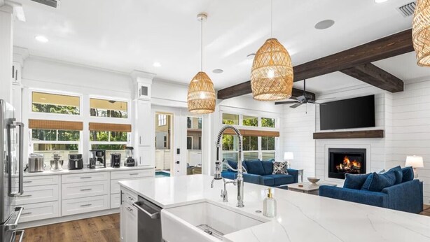 A modern kitchen with white cabinetry, a large island, and a dining area with blue sofas.