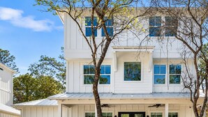 A two-story white building with a black front door, multiple windows, and a covered front porch.