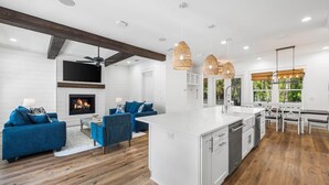 A modern kitchen with a central island, white cabinetry, and pendant lighting.