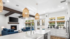 A modern kitchen with white cabinetry, a central island, and a fireplace. - Cote D' Azur • Private Pool Retreat on 30A • Golf Cart 🛺 (Seagrove Beach)