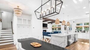 A modern kitchen with white cabinetry, a black dining table, and a chandelier. - Cote D' Azur • Private Pool Retreat on 30A • Golf Cart 🛺 (Seagrove Beach)