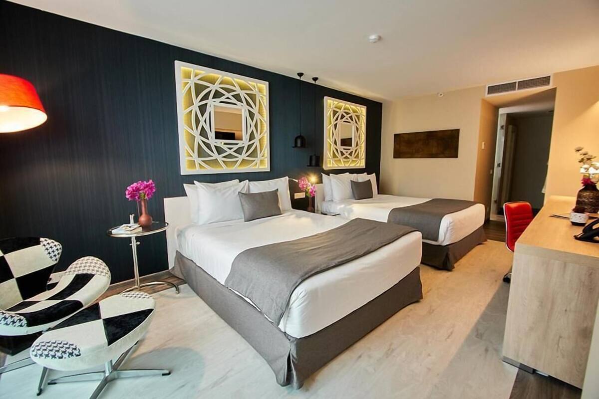 Een hotelkamer met twee bedden, een bureau, een stoel en decoratieve wandkunst.