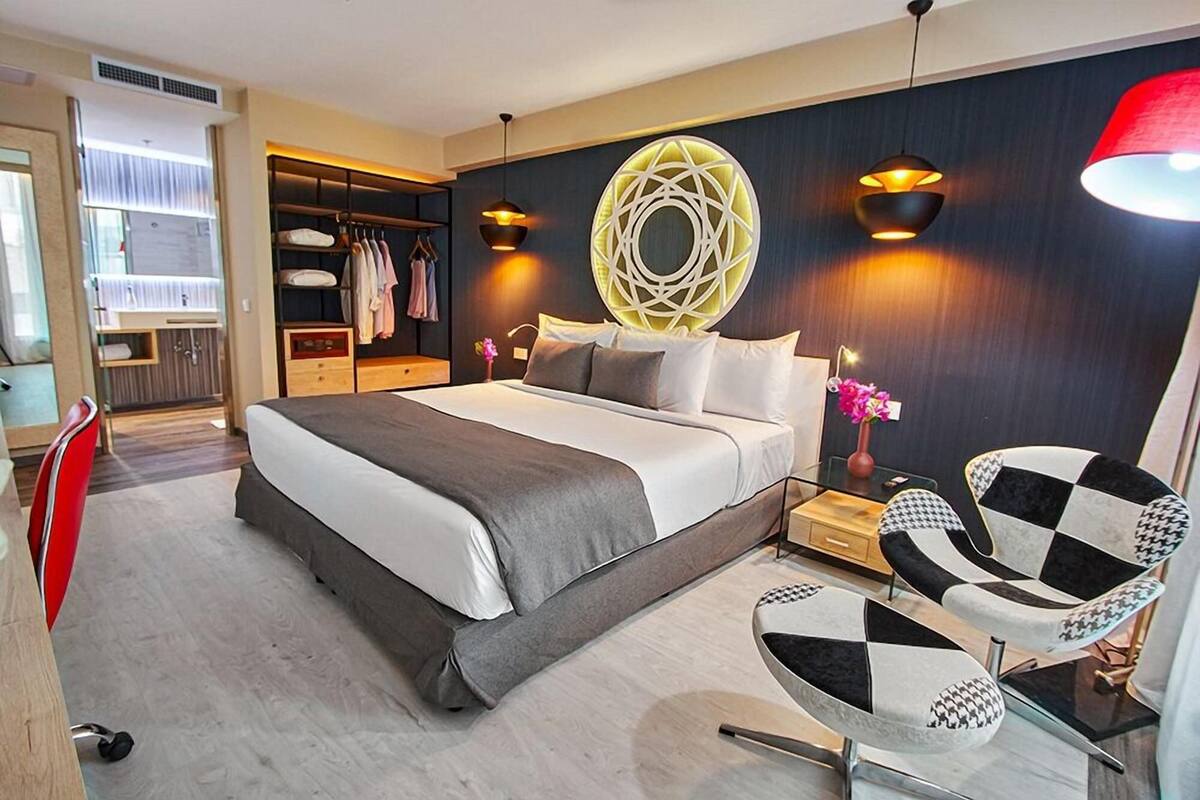 Een moderne hotelkamer met een groot bed, een kledingkast, een bureau en twee stoelen.