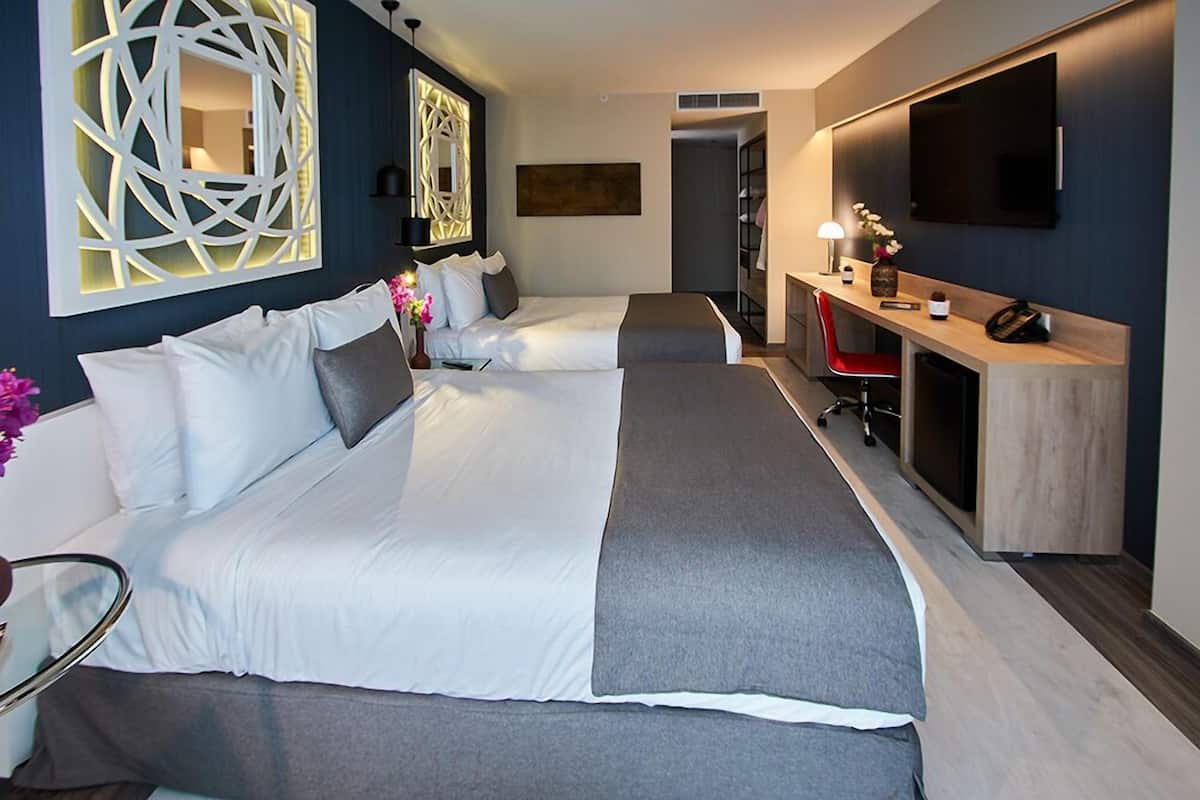 Une chambre d’hôtel moderne équipée de deux lits, d’un bureau, d’une télévision et d’un élément décoratif mural.