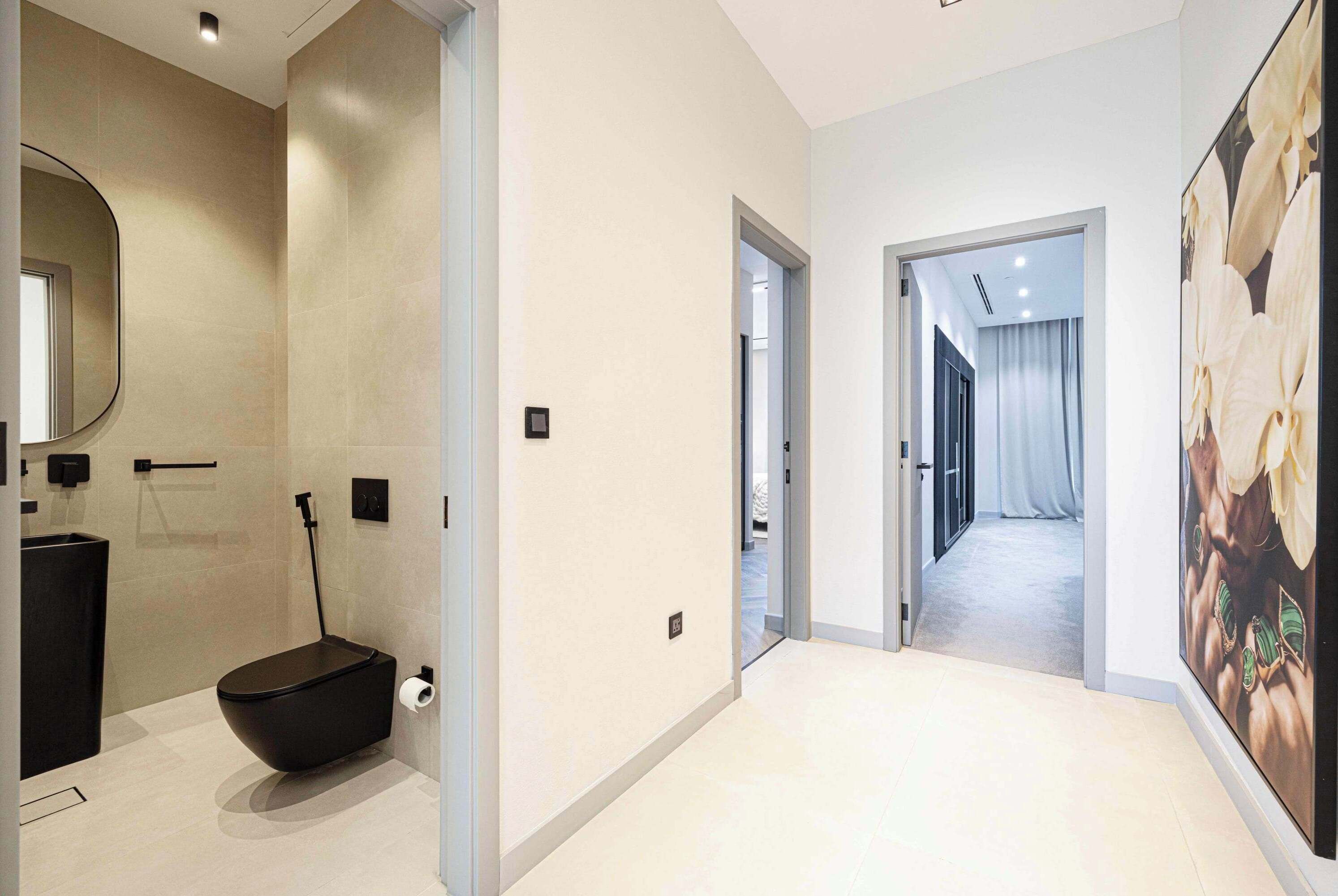 Une salle de bain moderne avec des toilettes noires, un grand miroir et un porte-rouleau de papier toilette.