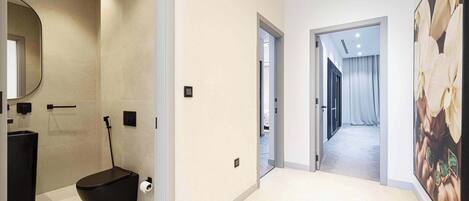 Une salle de bain moderne avec des toilettes noires, un grand miroir et un porte-rouleau de papier toilette.