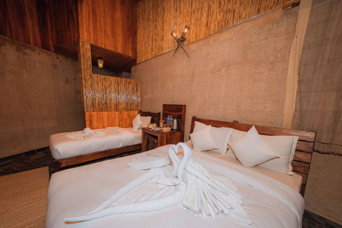A hotel room with two beds, wooden headboards, and a wooden ceiling.